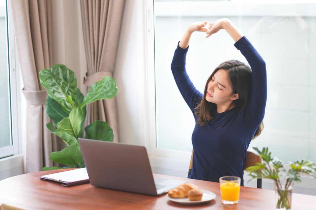 Young asian woman stretching relaxation resting office behind her desk working productive