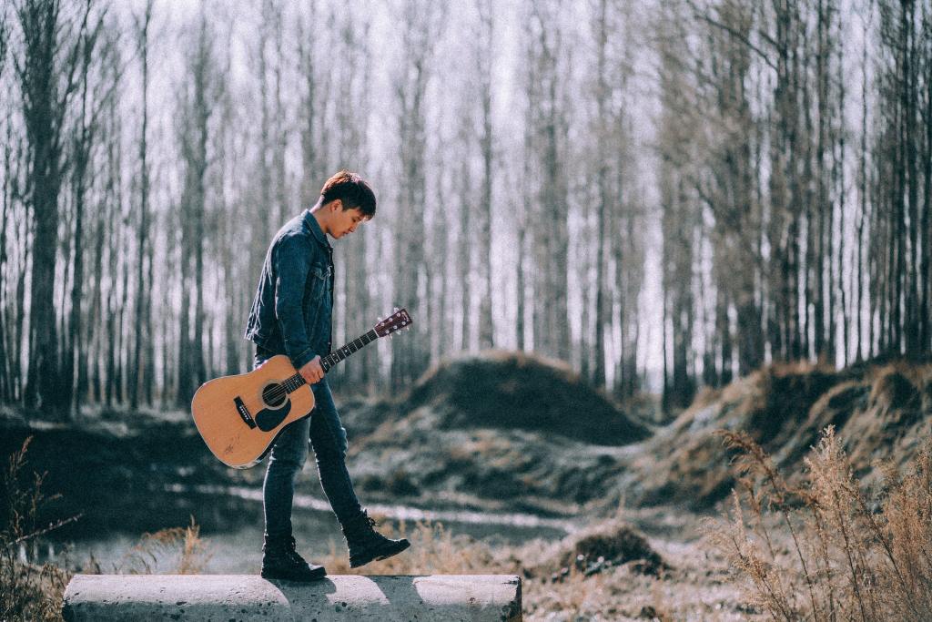 man in nature with acoustic guitar