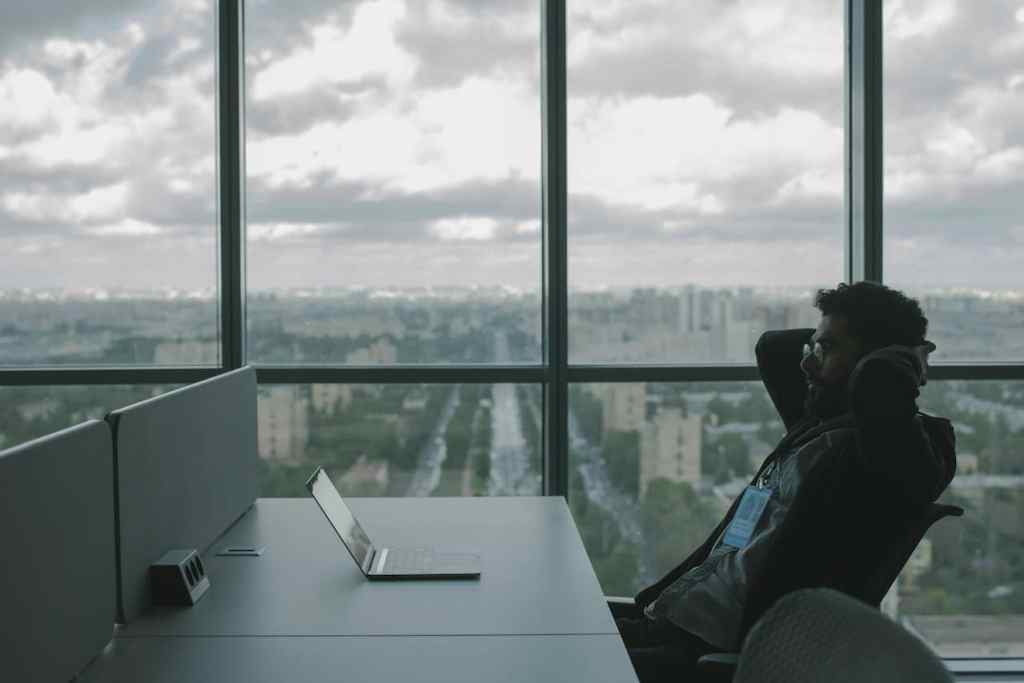 office worker sitting at minimal desk with window view accross the city and grey cloudy sky
