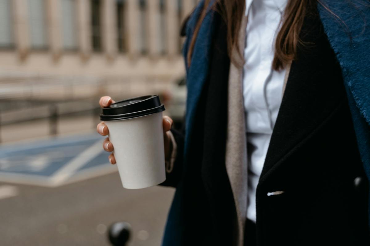 Woman walking to work with coffee, representing confidence and Monday Motivation at the start of the week.