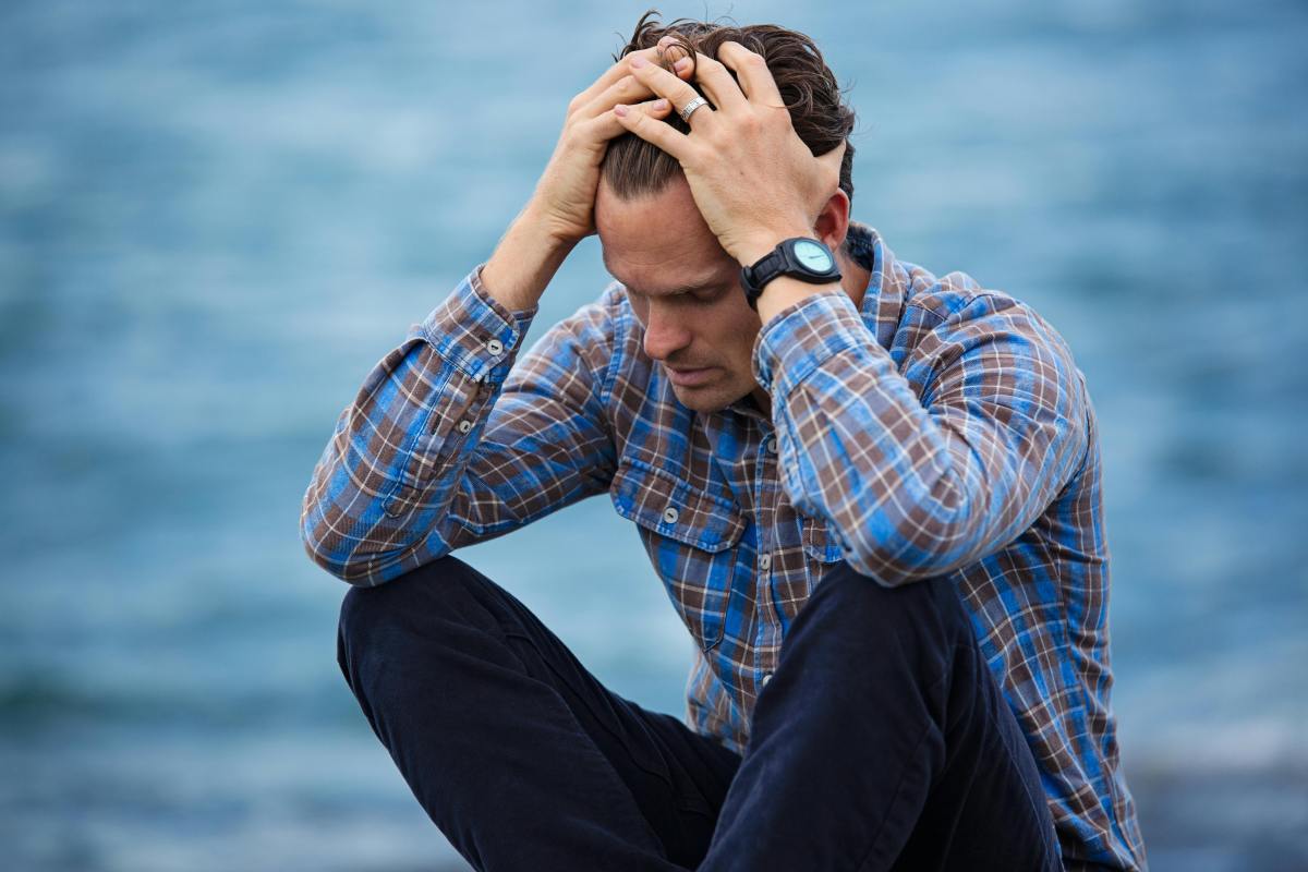 Stressed man running hand through hair, showing effects of chronic stress before starting a cortisol detox.