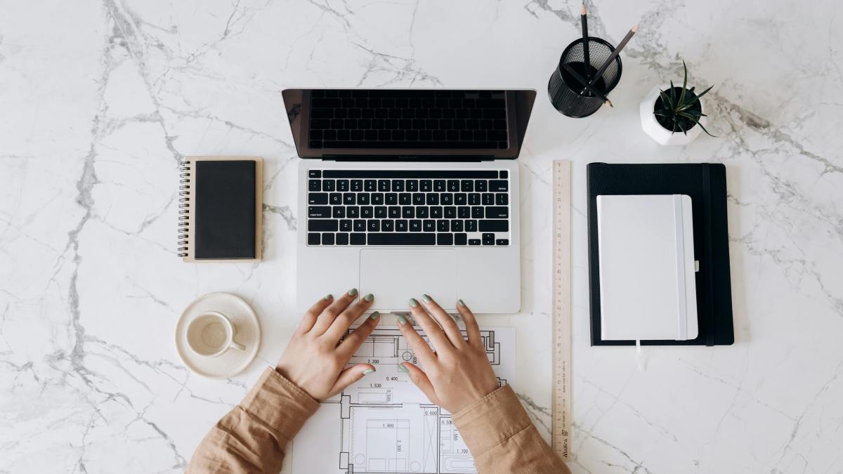 Person in a brown long-sleeve shirt working on a MacBook Pro beside a ceramic mug, illustrating calm productivity and digital minimalism.