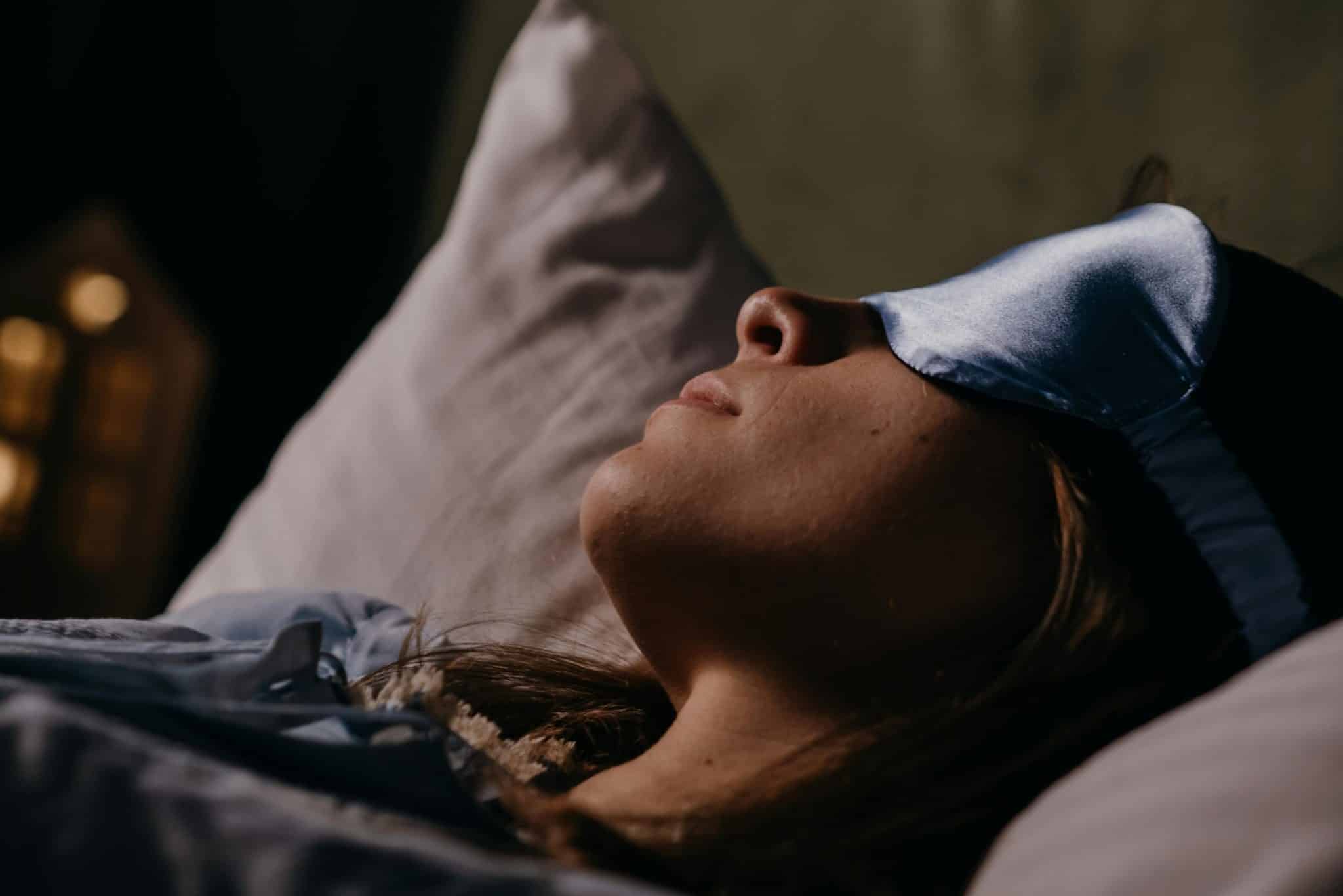 Woman asleep wearing an eye mask, symbolizing restful sleep avoiding insomnia.