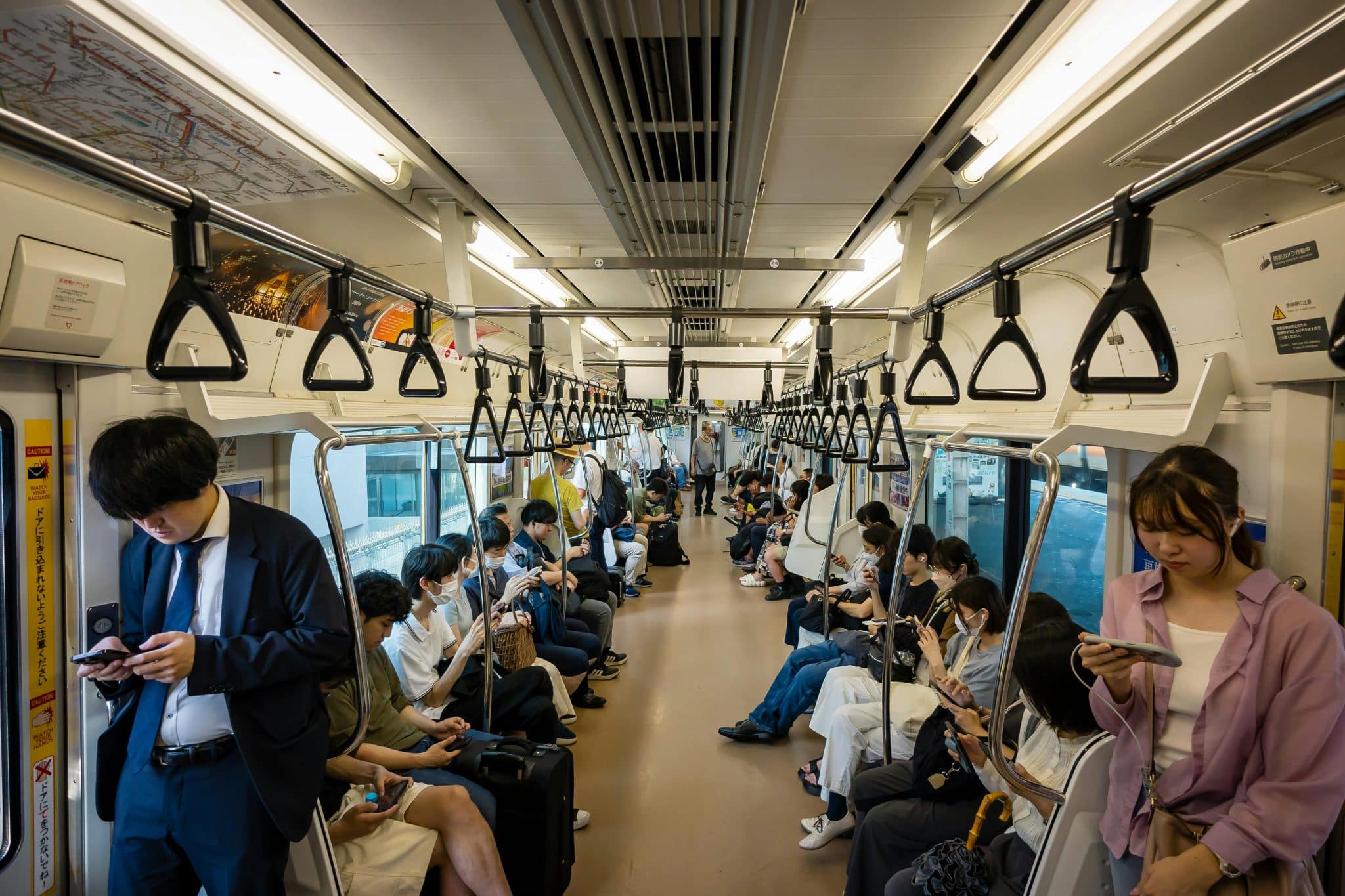 A crowded Japanese subway train filled with commuters absorbed in their smartphones, highlighting the global scale and everyday visibility of phone addiction.