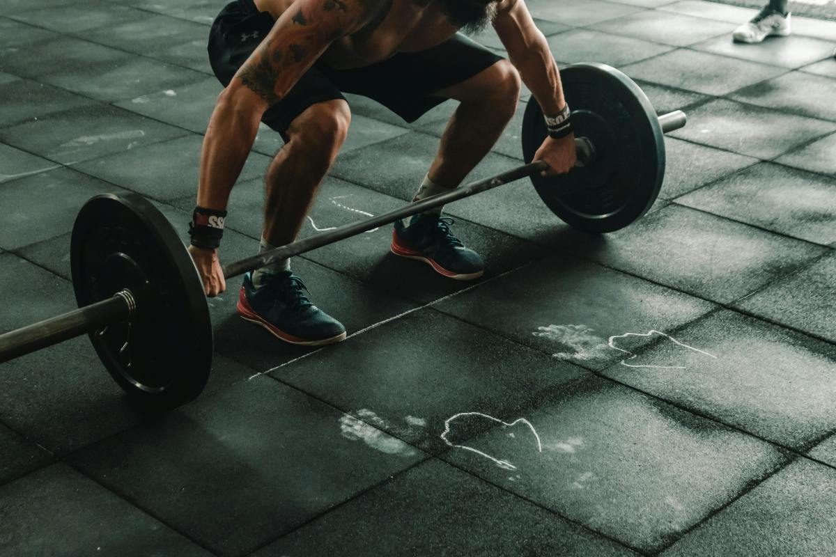 Man lifting barbell – building strength with consistent goal setting strategies.